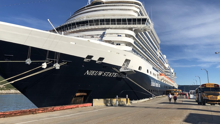 Un bateau de croisière imposant est accosté sur un quai. 
