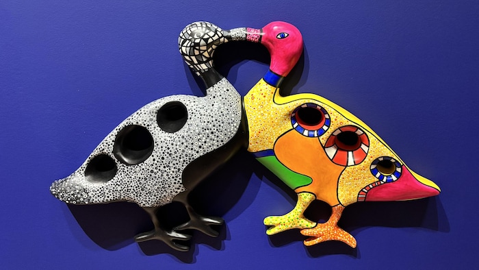 Une œuvre au mur de deux oiseaux collés par le bec.