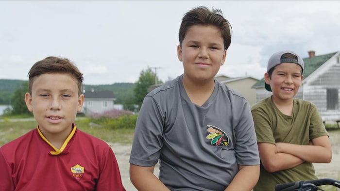 Trois jeunes garçons d'une douzaine d'années posent determination la photo.