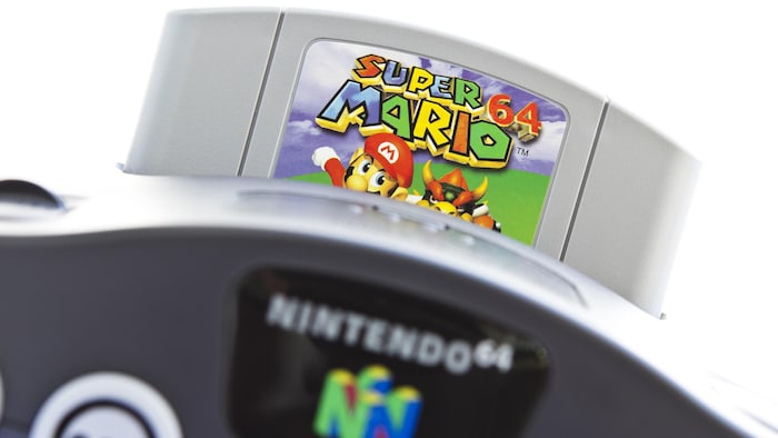 Une photo d'une console de jeux vidéo Nintendo 64 dans laquelle est insérée une cartouche du jeu Super Mario 64.