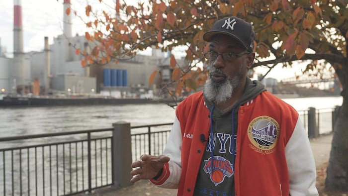 Un homme discute avec, en arrière-plan, une centrale électrique.