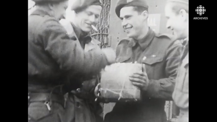 Des soldats souriants ouvrent un cadeau de Noël.