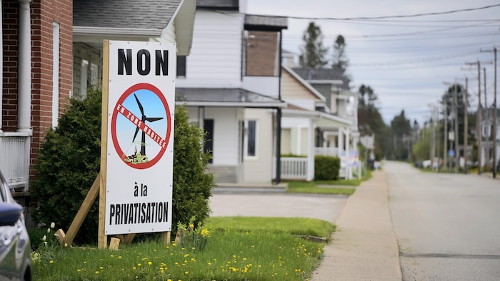 Une affiche sur laquelle est inscrit « Non à la privatisation en zone habitée » devant une maison.