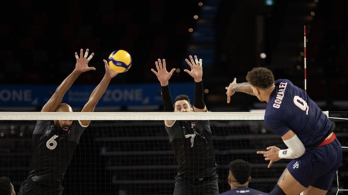 Des joueurs de volleyball sautent au filet.