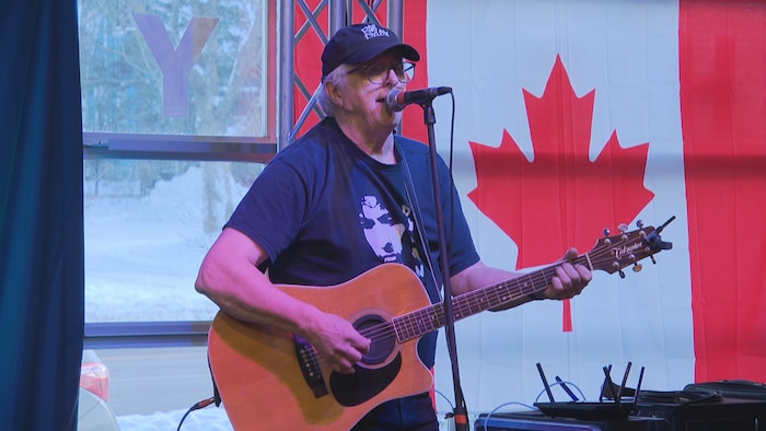 Chansonnier sur scène avec un drapeau du Canada à l'arrière. 