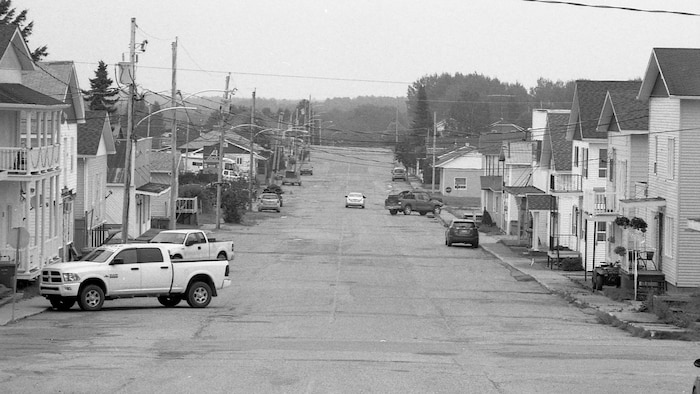 Photo en noir et blanc d'une rue bordée de maisons.