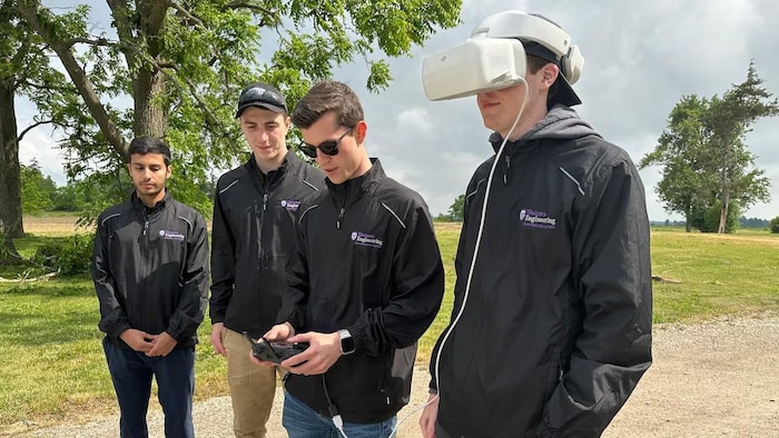 Quatre membres du Northern Tornadoes Project sur le terrain, dont l’un porte un casque de visualisation relié à l’équipement tenu par un collègue.