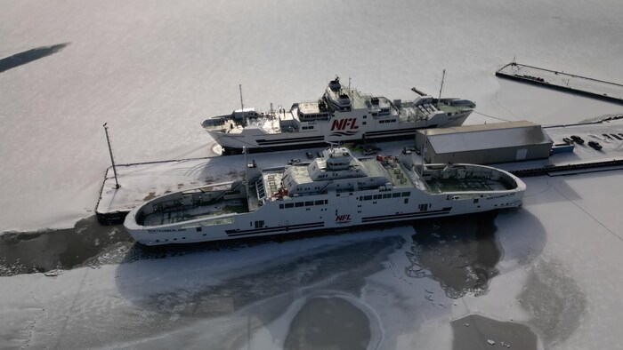 Deux traversiers à quai côte à côte dans l'eau gelée.