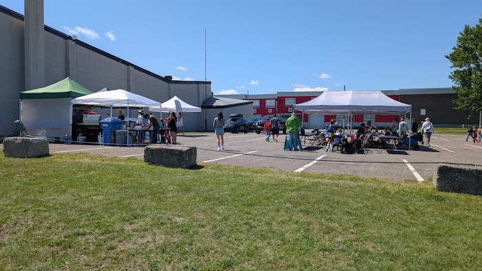 Deux tentes sur un stationnement avec un endroit pour manger et un barbecue.