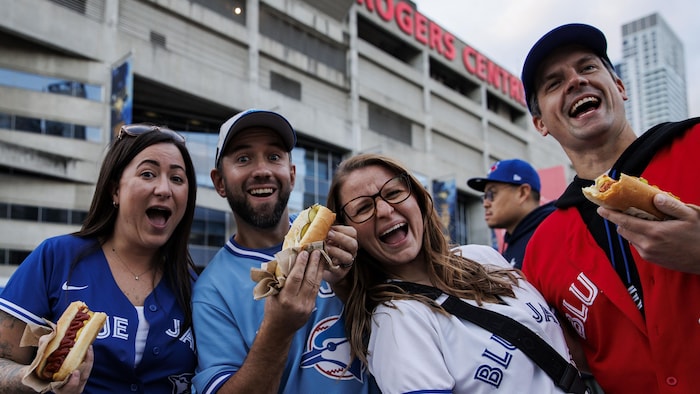 Des personnes portant les couleurs des Blue Jays devant le Centre Rogers en prévision du lucifer 7 de la série de championnat de la Ligue américaine de shot majeur, à Toronto, contre les Mariners de Seattle, le 20 octobre 2025.