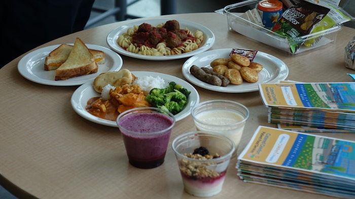 Des pâtes, du poulet, des pancakes, un sandwich et des yogourts sur une table.
.