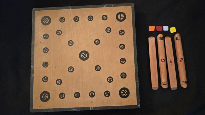 Un plateau de jeu en bois avec des caractères écrit en chinois. Des bâtonnets de bois sont posés à côté. 