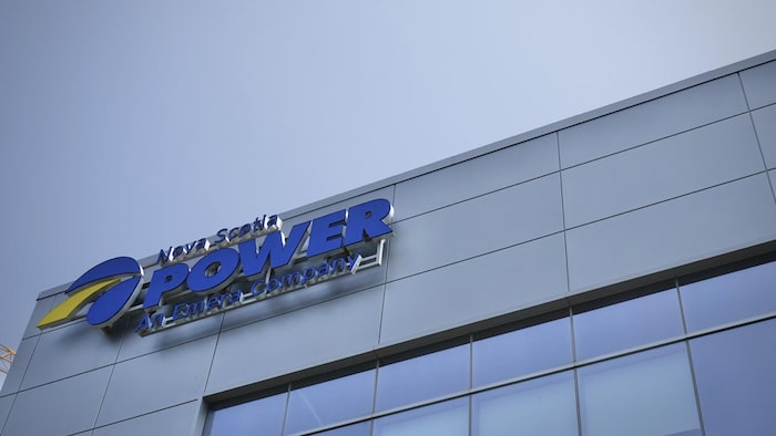 Le coin supérieur d'un édifice à bureaux gris métallique décoré du logo bleu avec une touche de jaune de Nova Scotia Power.