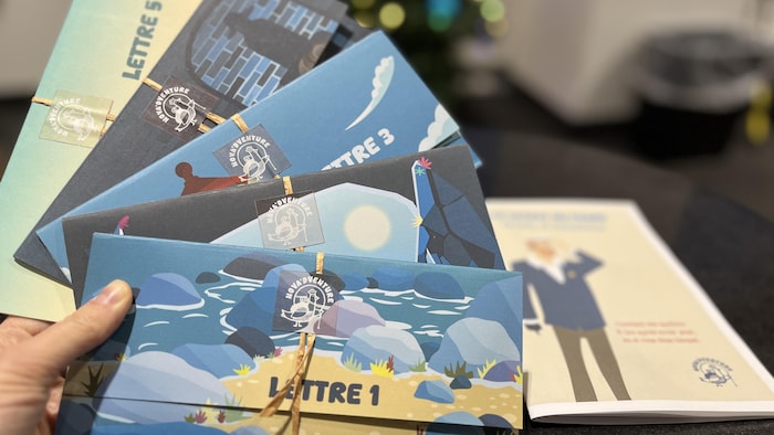 Une main tient cinq enveloppes illustr&eacute;es de couleurs vives et scell&eacute;es avec de petits rubans et des autocollants.