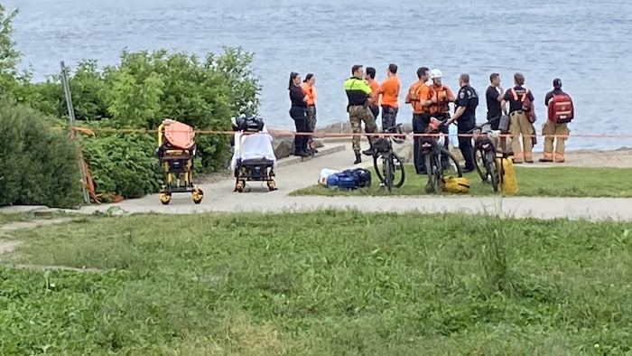 Des policiers sur le bord de la rive recherchent un homme.