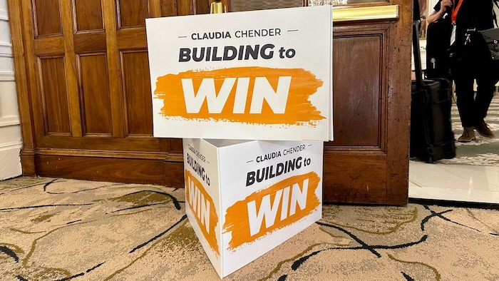 Deux pancartes blanches et orange avec les mots « Claudia Chender » et « Construire pour gagner » en anglais.
