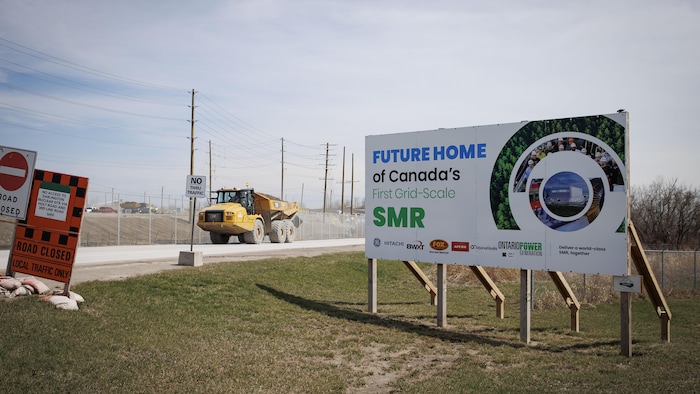 Des panneaux de signalisation sur un chantier de construction. Sur un panneau, on peut lire « Futur emplacement du premier PRM au Canada ». 
