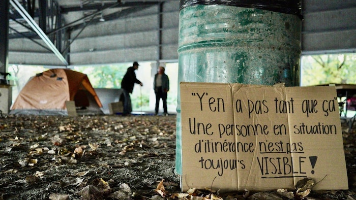 «"Y'en a pas tant que ça." Une personne en situation d'itinérance n'est pas toujours visible!». Des tentes sont installées en arrière-plan.
