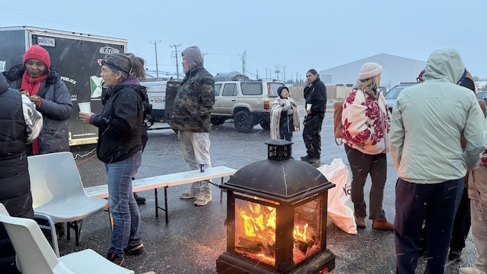 Des membres de la communauté innue de Uashat mak Mani-utenam et des résidents de Sept-Îles sont rassemblés autour d'un feu.