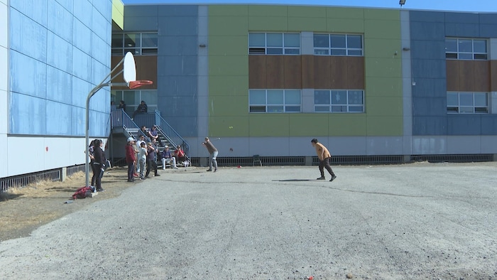 Les jeunes jouent au baseball dans la cour d'école. 
