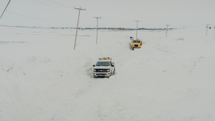 Deux camions sur une petite route bordée de neige à Puvirnituq, le 19 mai 2025.