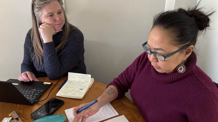 Deux femmes assises à une table avec des notes papier discutent le 26 février 2025.