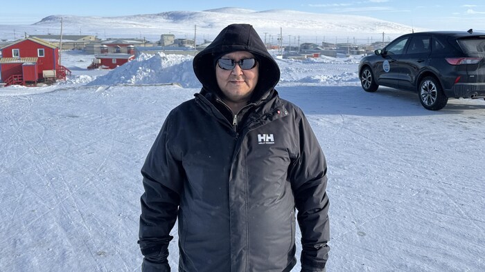 Un homme se tient debout dans un stationnement, à Clyde River, au Nunavut, le 11 avril 2025.