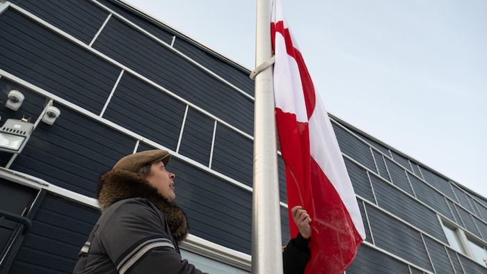 Le président de l’Assemblée législative du Nunavut hisse un drapeau groenlandais devant l’Assemblée législative territoriale.