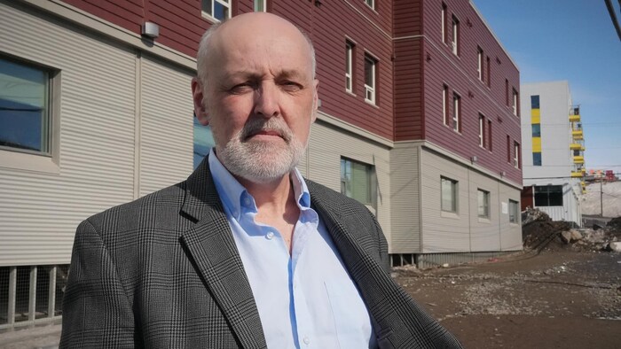 Un homme se tient debout devant un bâtiment d'Iqaluit, le 17 avril 2024.