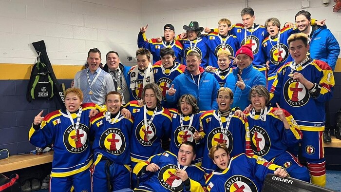 Les joueurs de l'équipe du Nunavut regardent vers l'appareil photo avec leur médaille autour du cou.