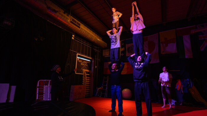Cinq personnes sont en équilibre durant une répétition d'un spectacle de cirque, à Igloolik, au Nunavut. 