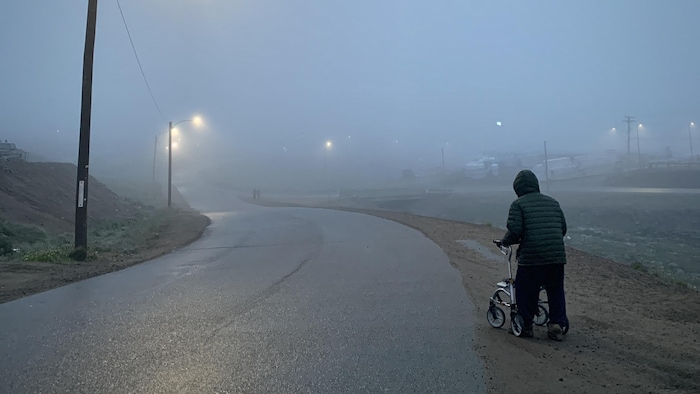 Un homme âgé marche dans une rue d'Iqaluit à l'aide d'une marchette.