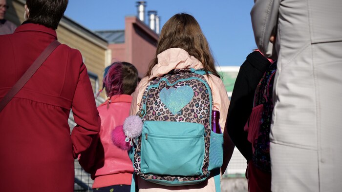 Une élève de dos se tient devant l'École des Trois-Soleils d'Iqaluit le jour de sa rentrée scolaire. 