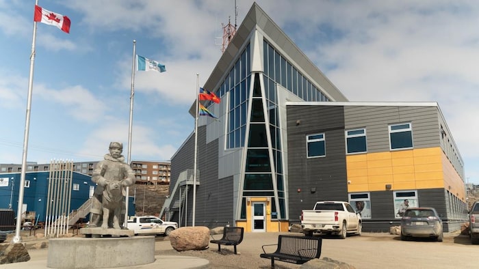 Des drapeaux volent dans le vent devant le bâtiment extérieur du détachement de la Gendarmerie royale du Canada (GRC) à Iqaluit, au Nunavut, en été.