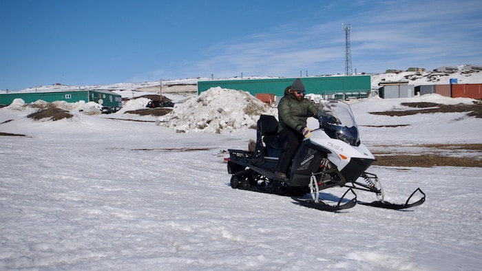 Un homme est assis sur une motoneige électrique et conduit dans un sentier enneigé, à Iqaluit, au Nunavut, le 16 avril 2024.