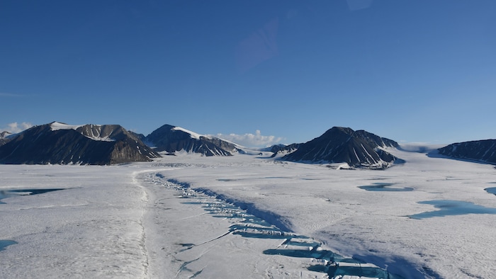 Une vue aérienne d'une étendue de glace et d'une chaîne de montagnes.