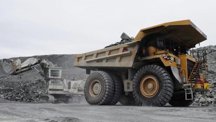 Un camion lourd transporte de la roche dans une carrière.