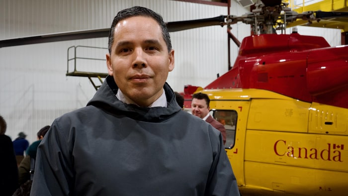 Le président de l'organisme national Inuit Tapiriit Kanatami, Natan Obed, se tient devant un hélicoptère dans un hangar des forces armées canadiennes à Iqaluit, au Nunavut, le 18 mars 2025.