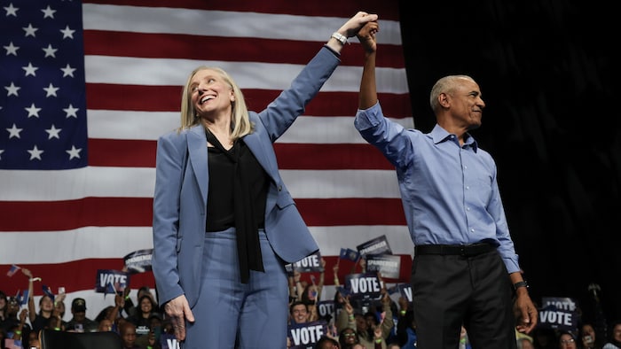 L'ancien président américain Barack Obama et la gouverneure démocrate de Virginie, Abigail Spanberger se tiennent la main devant des partisans.