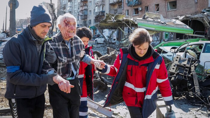 Rescuers help a man injured in the shelling of a residential building in kyiv on March 14, 2022.