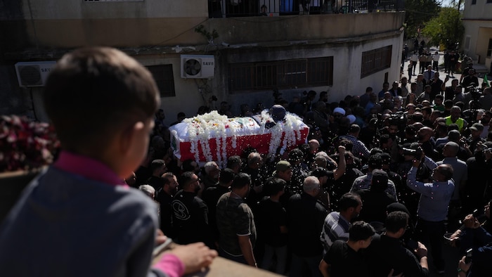 Une foule endeuillée porte un cercueil.