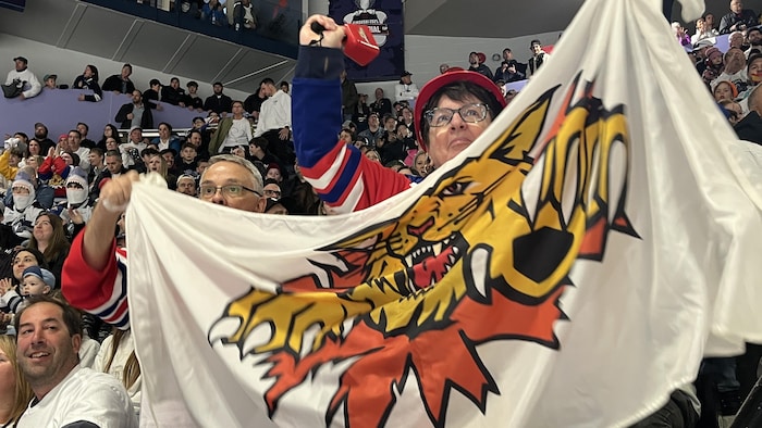 Deux partisans tiennent un drapeau des Wildcats de Moncton.