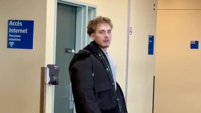 Le jeune homme enfile son manteau.