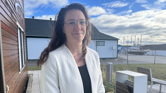 Odessa Thériault souriant à l'extérieur devant des bateaux.