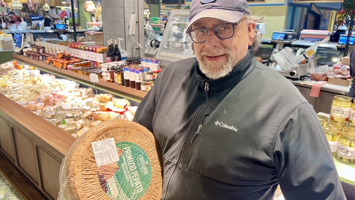 Odysseas Gounalakis pose devant la caméra avec un gros fromage.