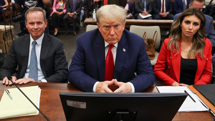 Donald Trump est assis dans la salle d'audience entre deux avocats.