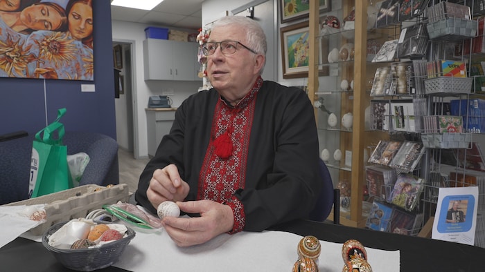 Paul Gagné est assis à une table avec un pysanky à la main.