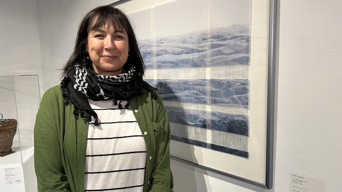 Julie Forgues pose pour la photo devant une œuvre.