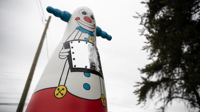 Une sculpture en forme de clown qui tient un miroir.