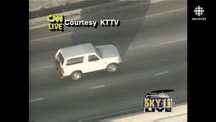 Vue aérienne de la camionnette Ford Bronco blanche qui roule sur l'autoroute. En surimpression à l'écran, les logos des sources de la diffusion : CNN, KTTV et SKY 11.